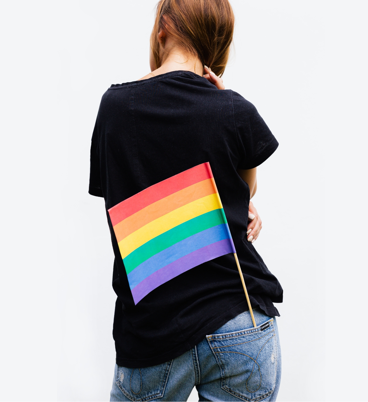 Girl wearing black t-shirt and jeans with a pride flag in her pocket